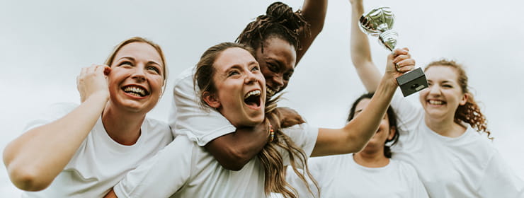 A women's football team celebrating with a trophy